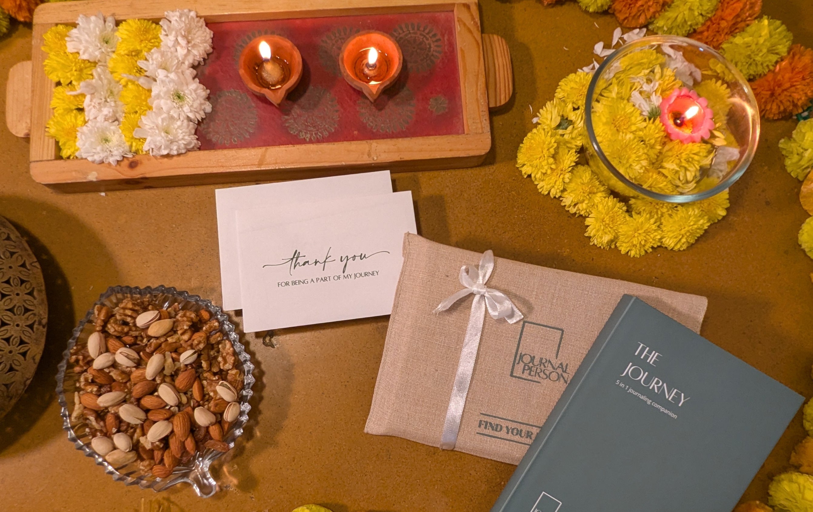 Decorative setup with flowers, candles, and a card on a wooden surface.